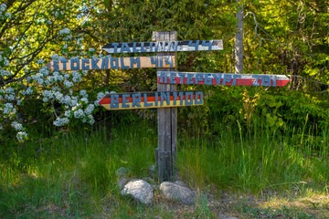 Handmade wooden sign with directions (Tallinn, Stockholm, Saint Petersburg, Berlin) at sunny summer day. Selective focus.