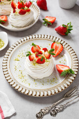 Perfect mini Pavlova cake with whipped mascarpone cream and fresh strawberry slices, sprinkled with crushed pistachios.