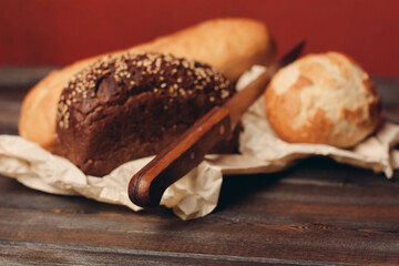 gray bread on paper packaging on wooden table and red background in the background kitchen knife
