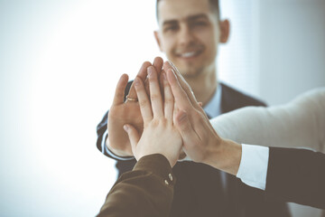Fototapeta premium Business people group showing teamwork and joining hands or giving five in modern office. Unknown businessman and women making circle with their hands