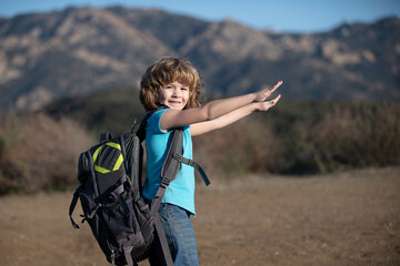 little boy with backpack hiking in scenic mountains. Kid local tourist goes on a local hike.