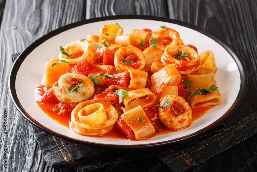 Wall mural portion of italian calamarata pasta with squid rings and tomato close-up in a plate on the table. ho