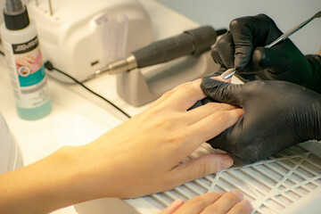 Finger cuticle treatment with manicure tools in a professional salon.