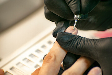 Nail treatment with a manicure machine in a professional salon.