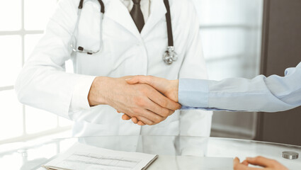 Unknown male doctor and woman-patient discussing current health examination while sitting in clinic and using clipboard. Good medical service in hospital. Medicine concept