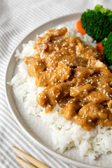 Homemade Orange Chicken with White Rice, Broccoli and Carrot on a plate, side view.