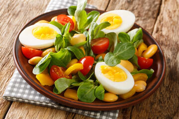 Homemade boiled eggs and salad of lupine beans, tomatoes and feldsalat close-up in a plate on the table. horizontal