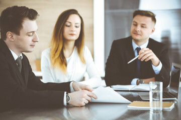 Business people or lawyers discussing questions at meeting in modern office. Unknown businessman and woman with colleague sitting and working at the glass desk. Teamwork and partnership concept