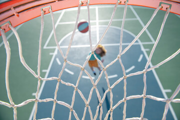 Top view of flying ball to basket from kid play basketball.