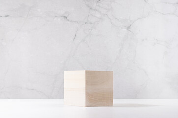 Elegant podium of beige wooden cube on white board and grey marble wall for product display. Simple modern minimalistic design.