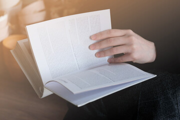 Woman reading a book, girl holds white book while reading at home. Reading mock up , close up details. 