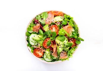 Fresh salad with salted salmon, avocado, cucumber, sesame seeds, olive oil, tomatoes and mixed herbs. White background, top view, copy space