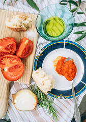 Vegetarian low-calorie still life with red tomatoes ,olive oil, garlic, onion and big spoon of AJVAR - traditional Balkans countries popular side dish.