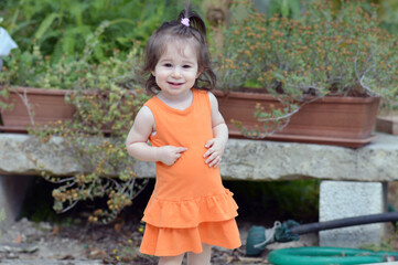 Ritratto all'aperto di una bambina che indossa un vestitino arancione.
