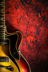 Old, jazz electric guitar on a red grunge background. Copy space. Background for music festivals,...