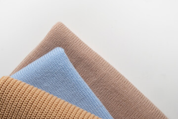 A stack of 3 wool sweaters in beige and blue colors.