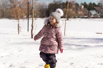 Fototapeta na wymiar happy little girl playing in the snow on a winter sunny day