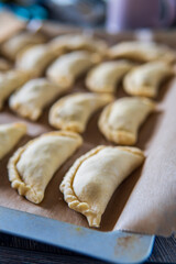 Raw uncooked empanadas on a baking tray. Traditional Latin American baked beef pastry ready for the oven. Gluten free savory appetizer with meat filling. Handmade typical dish in Spain or Argentina.
