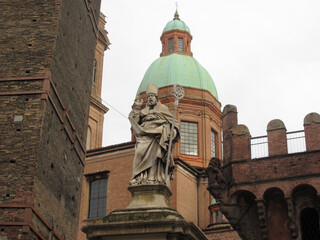 The statue of Saint Petronius ( San Petronio ) between the Asinelli tower and the Garisenda tower . Bologna, Italy