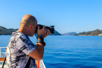 Obraz premium Travel photographer man with professional camera taking photos of the Mediterranean Sea in Antalya province, Turkey