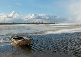 Fototapeta na wymiar winter landscape with lake, old wooden boat in the lake, expressive clouds, Lake Burtnieki