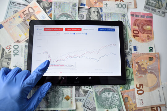 WROCLAW, POLAND - 4th FEBRUARY 2021: illustrative photo tablet with funds charts and cash polish zlotych, euro and dollars.