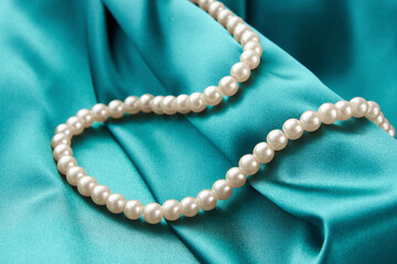 Pearl necklace on green background, close-up