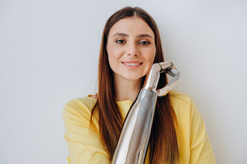 Attractive long haired lady with contemporary bionic prosthesis arm looks into camera standing on...