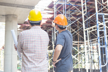 Naklejka na ściany i meble Three engineers working in a construction site