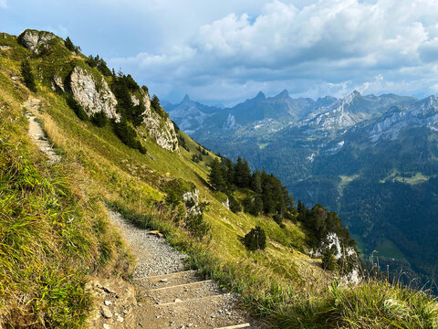 Hiking path with stairs in Swiss Alps. Breathtaking view of the peaks of the mountains in sunny summer day.