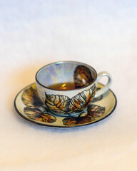 decorated tea mug with saucer on a white background