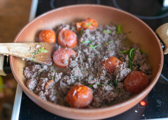 a pan of roast meat with red tomato pieces
