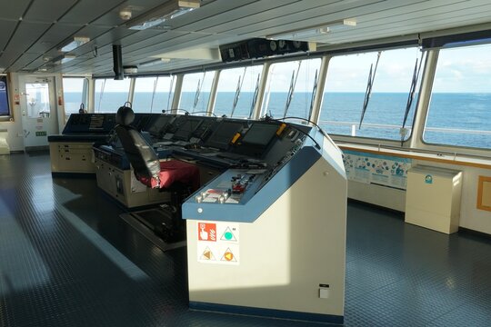 The Modern Ship’s Bridge control console with navigational equipment of container ship with view on the sea.