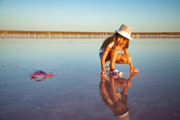 A little beautiful girl is looking at something in a transparent water surface on a transparent background