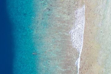 Wave on coral beach beautiful natural shore, coast background at the summer time. Tropical nature pattern, sea ocean surface, top aerial view. Blue shades with surf waves
