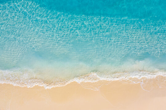 Summer seascape beautiful waves, blue sea water in sunny day. Top view from drone. Sea aerial view, amazing tropical nature background. Beautiful bright sea with waves splashing and beach sand concept