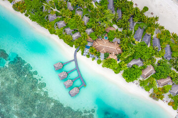 Luxury overwater villas with coconut palm trees, blue lagoon, white sandy beach at Maldives islands. Top view, summer vacation, holiday landscape. Amazing relaxing nature aerial scene, traveling scene