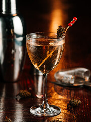 whiskey cocktail with pine cone decor. On a wooden table.