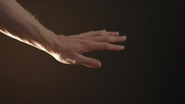 Slow motion man hand playing with sun light on a black background