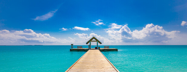 Tropical pier to paradise island beach. Amazing ocean lagoon, sea horizon under blue sky. Idyllic, meditation, inspiration scenery. Wellbeing, relaxation, positive thinking. Travel, summer wellness