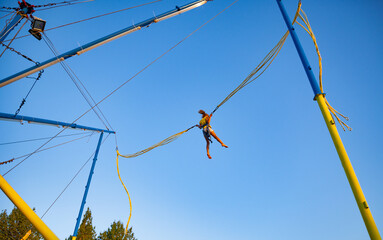 Little girl flies on elastic bands and jumps on a trampoline