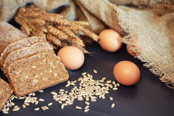 Fresh loaves of bread with wheat and gluten on a black table. Bakery and grocery concept. Fresh,...