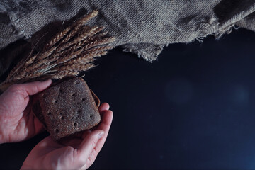 Fresh loaves of bread with wheat and gluten on a black table. Bakery and grocery concept. Fresh, healthy sorts of rye and white loaves food closeup. Fresh homemade bread with cereals.