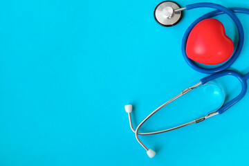 Yearly health check up, disease diagnosis medicine, healthcare and cardiology concept with a red heart and a stethoscope isolated on a hospital blue background with copy space
