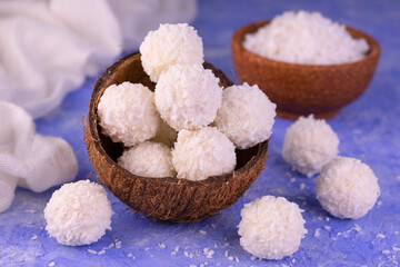 Coconut candies in a coconut shell on a blue front. Close-up.