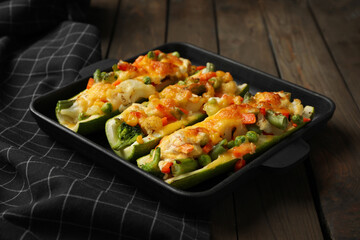 Baking dish with stuffed zucchinis served on wooden table, closeup