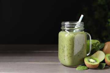 Delicious kiwi smoothie and ingredients on wooden table. Space for text