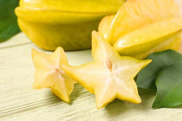 Delicious carambola fruits on yellow wooden table, closeup