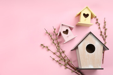 Obraz na płótnie Canvas Beautiful bird houses and pussy willow branches on pink background, flat lay. Space for text