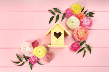 Stylish bird house and fresh eustomas on pink wooden background, flat lay